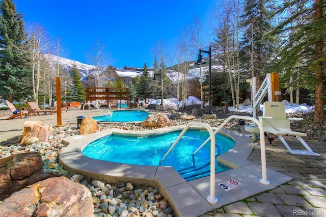 community pool with a patio area and a hot tub