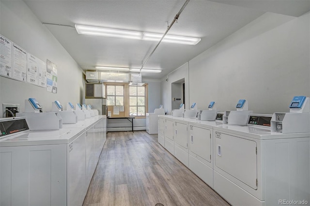 community laundry room featuring separate washer and dryer and light wood finished floors