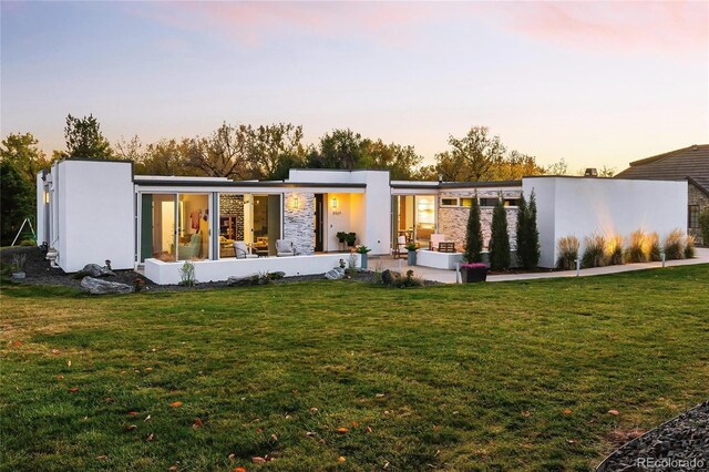 back of house at dusk with a lawn