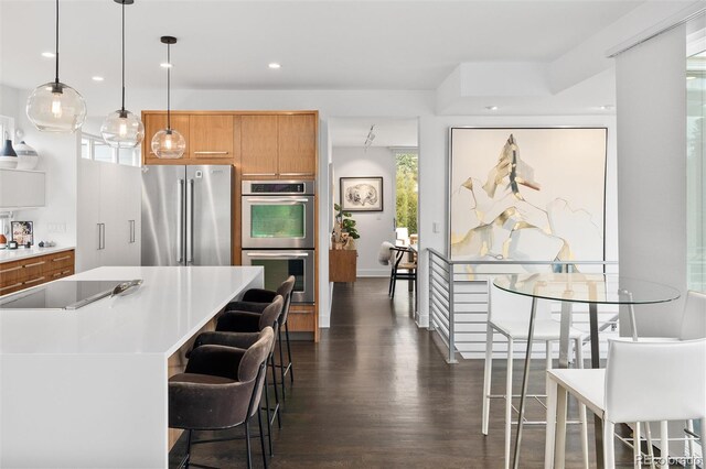 kitchen featuring a breakfast bar area, a center island, dark wood finished floors, light countertops, and stainless steel appliances