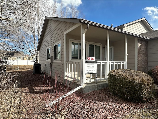 view of side of property featuring fence, central AC unit, and brick siding