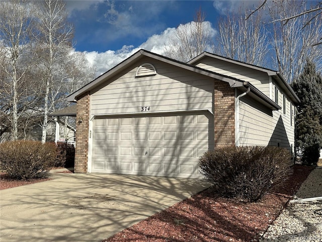 view of side of home featuring a garage, brick siding, and driveway