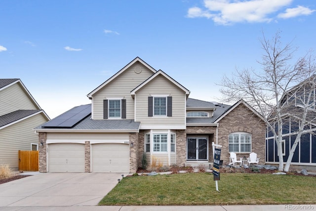 view of front facade with fence, brick siding, concrete driveway, a front yard, and solar panels