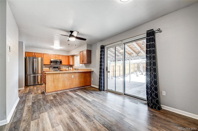 kitchen featuring dark hardwood / wood-style floors, stainless steel appliances, kitchen peninsula, and ceiling fan