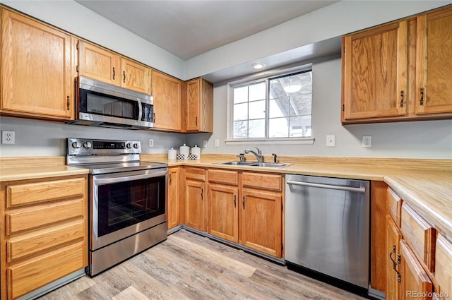 kitchen with sink, stainless steel appliances, and light hardwood / wood-style floors