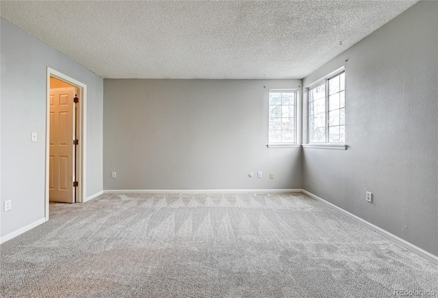 carpeted empty room featuring a textured ceiling