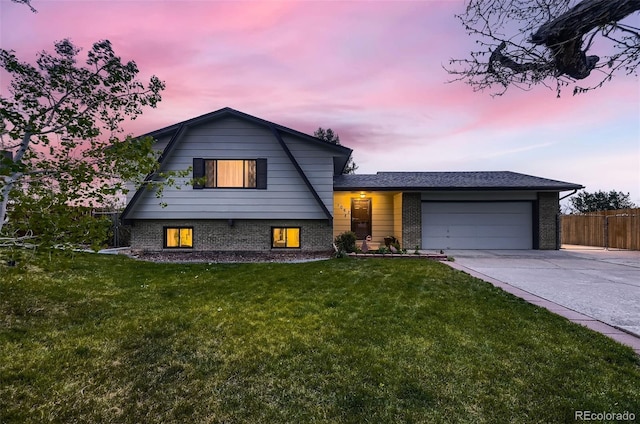 tri-level home featuring a lawn, brick siding, an attached garage, and driveway