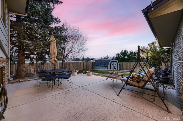 view of patio / terrace with outdoor dining area, a fenced backyard, a shed, and an outbuilding