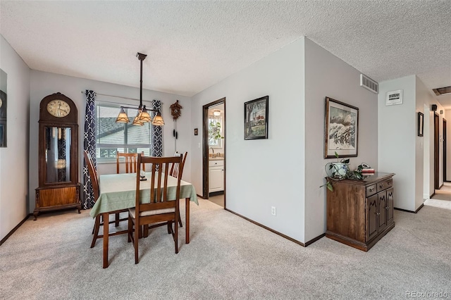 dining space featuring visible vents, a textured ceiling, and light carpet