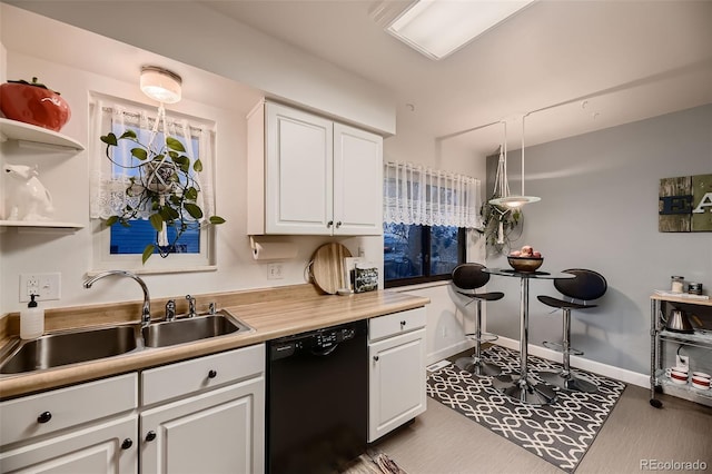 kitchen with dishwasher, a sink, light countertops, white cabinets, and baseboards