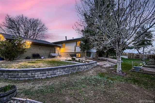 yard at dusk with fence and a patio area