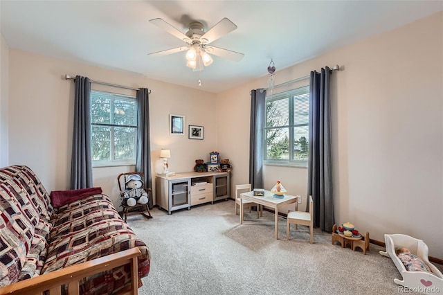 living area with ceiling fan, light colored carpet, and a healthy amount of sunlight