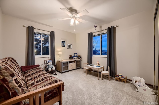 living area featuring light colored carpet and ceiling fan