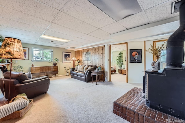 carpeted living area featuring a wood stove and a drop ceiling