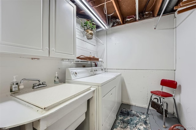 washroom with cabinet space, a sink, and washing machine and clothes dryer