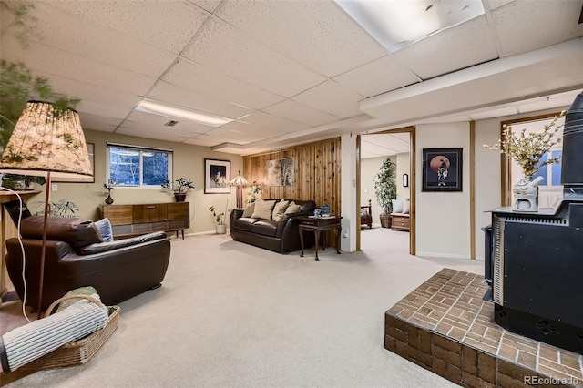 living room with a wood stove, a paneled ceiling, and carpet flooring