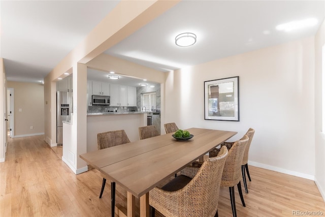 dining area featuring light wood finished floors and baseboards