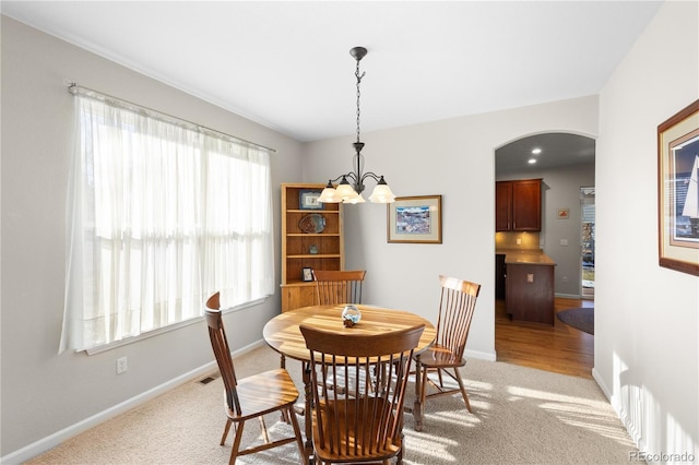 dining room with light colored carpet and an inviting chandelier