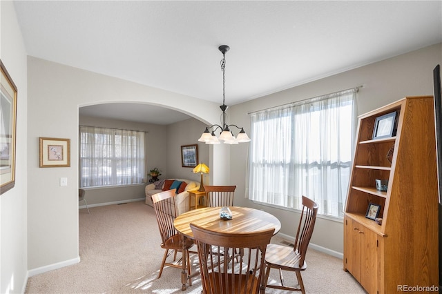 dining room with light carpet and a notable chandelier