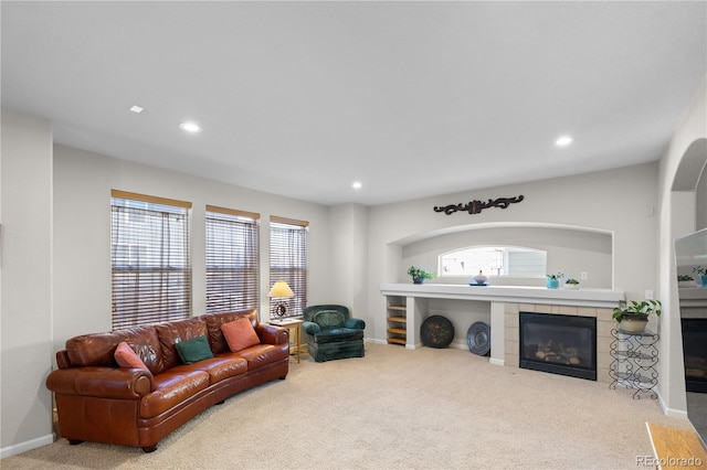 living room with a tile fireplace and light colored carpet