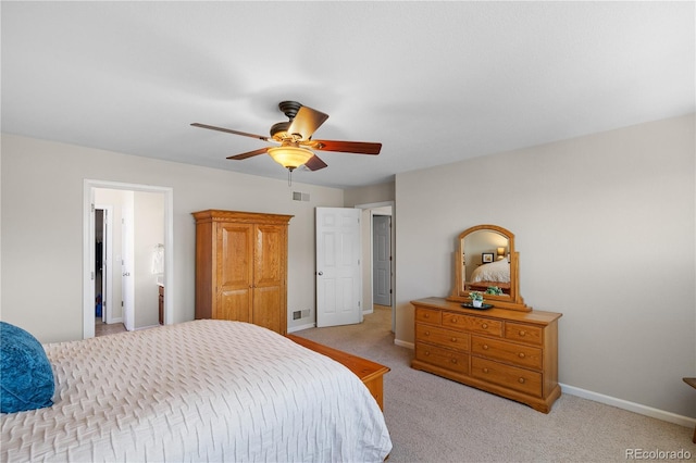 bedroom with ceiling fan, light colored carpet, and ensuite bath