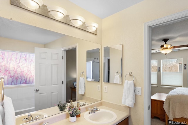 bathroom with ceiling fan, a tub to relax in, and vanity