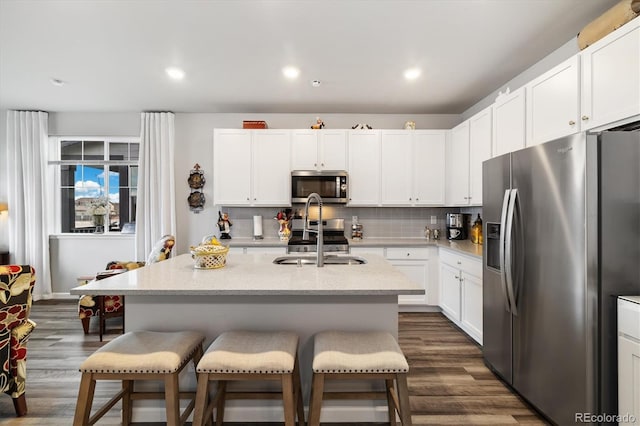 kitchen with a sink, dark wood finished floors, appliances with stainless steel finishes, and a kitchen breakfast bar
