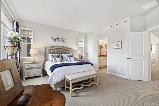 bedroom featuring baseboards, ensuite bathroom, and light carpet