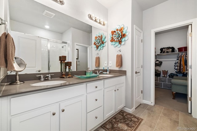 full bathroom featuring a sink, a walk in closet, a shower stall, and double vanity