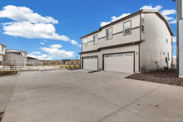 view of side of home featuring concrete driveway and a garage