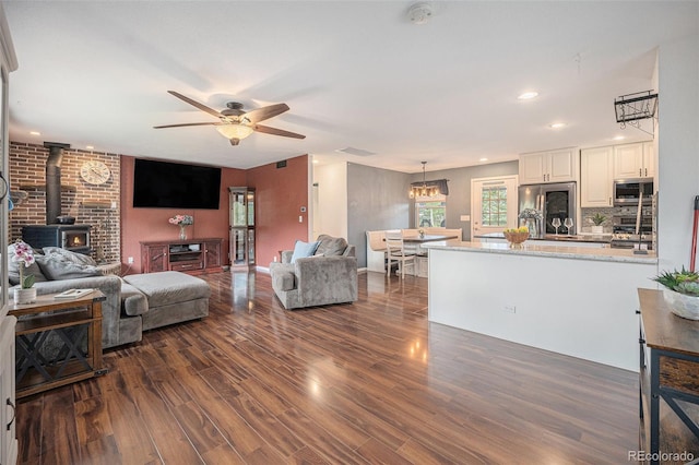 9075 Jill Dr, Conifer, CO 80433 - living room with a wood stove, dark wood-type flooring, ceiling fan, recessed lighting, and a chandelier