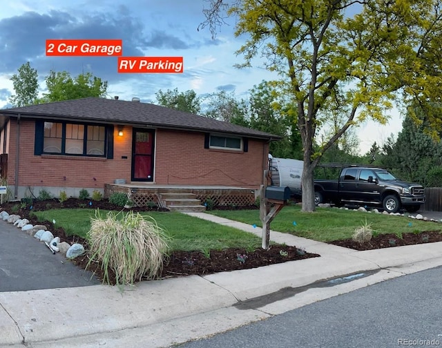 view of front of home featuring brick siding, roof with shingles, and a front yard