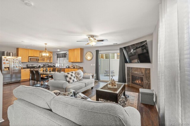 living room featuring a tile fireplace, ceiling fan, and dark hardwood / wood-style flooring