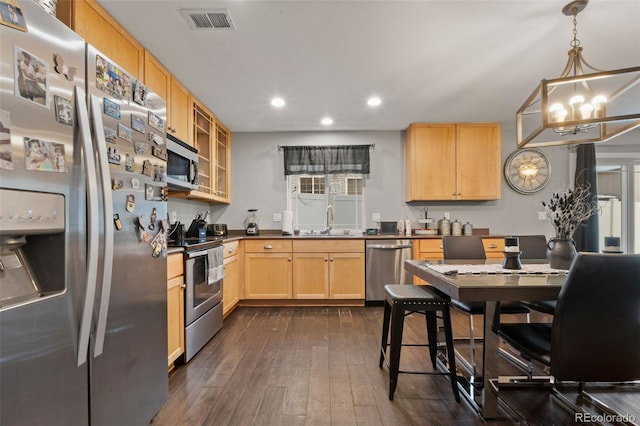 kitchen with appliances with stainless steel finishes, dark hardwood / wood-style floors, pendant lighting, light brown cabinetry, and sink