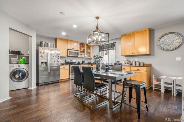 kitchen featuring washer / clothes dryer, hanging light fixtures, stainless steel appliances, and dark hardwood / wood-style floors