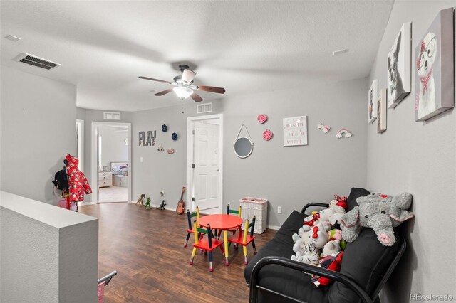 game room featuring ceiling fan, dark hardwood / wood-style flooring, and a textured ceiling