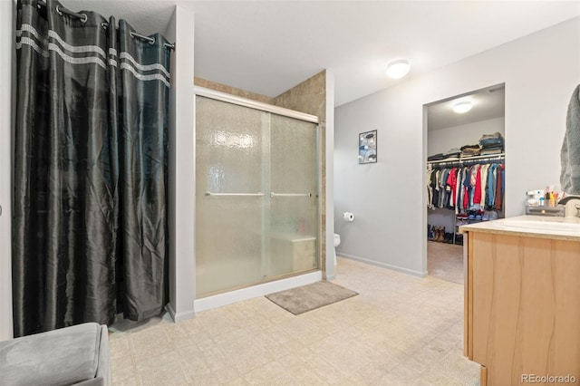 bathroom with walk in shower, vanity, and toilet