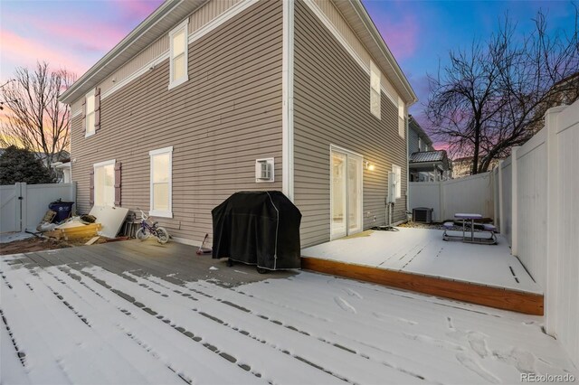 snow covered back of property with a wooden deck and central air condition unit