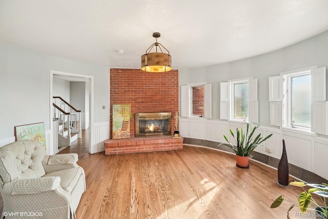 22081 Paradise Cir, Golden, CO 80401 - living area featuring stairway, light wood-style flooring, a decorative wall, a brick fireplace, and a wainscoted wall