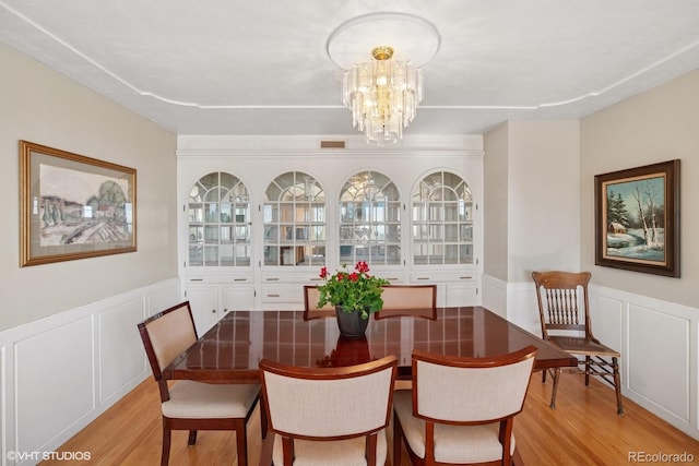 22081 Paradise Cir, Golden, CO 80401 - dining room with light wood-style floors, a decorative wall, a chandelier, and a wainscoted wall