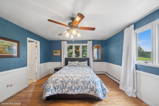 22081 Paradise Cir, Golden, CO 80401 - bedroom featuring multiple windows, a baseboard radiator, and wood finished floors