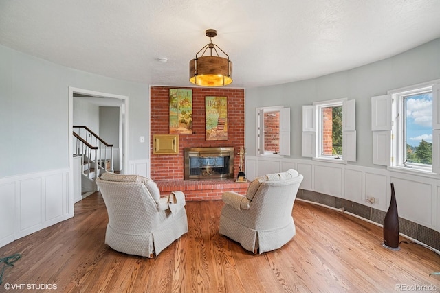 22081 Paradise Cir, Golden, CO 80401 - living area with a fireplace, a decorative wall, stairway, light wood-style floors, and wainscoting