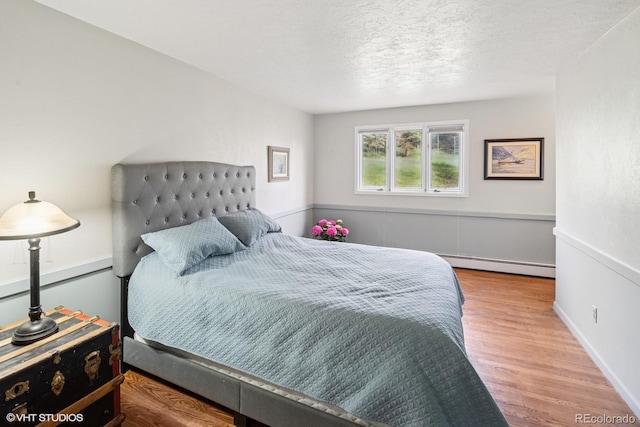 22081 Paradise Cir, Golden, CO 80401 - bedroom featuring baseboard heating, wood finished floors, and a textured ceiling