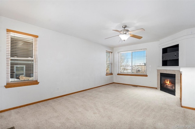 unfurnished living room with light colored carpet, ceiling fan, and a tiled fireplace