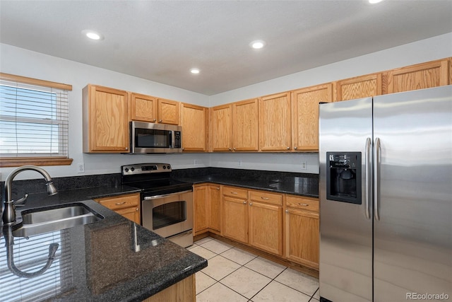 kitchen with dark stone countertops, light tile patterned floors, sink, and appliances with stainless steel finishes