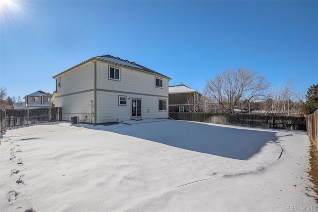 snow covered back of property featuring central AC