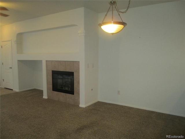 unfurnished living room featuring ceiling fan, carpet floors, and a tile fireplace