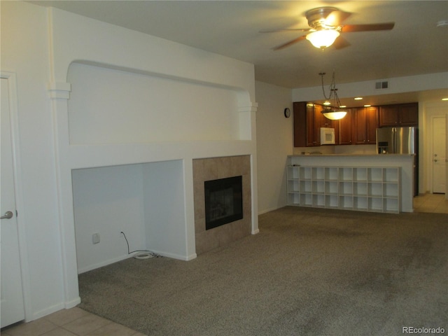 unfurnished living room featuring ceiling fan, a fireplace, and light carpet