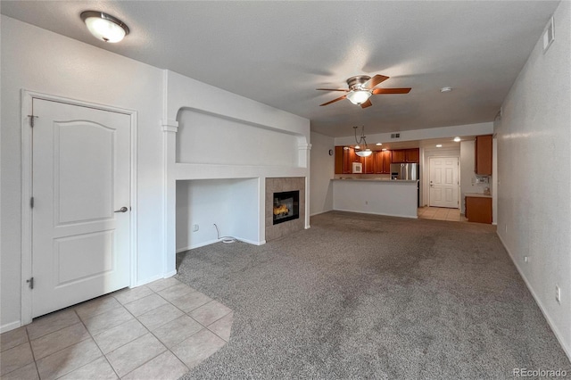 unfurnished living room featuring a textured ceiling, a fireplace, light colored carpet, and ceiling fan