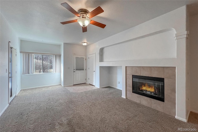 unfurnished living room featuring ceiling fan, a fireplace, light carpet, and a textured ceiling